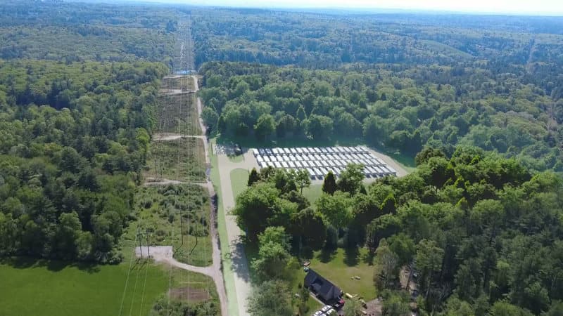 A rendering of the battery storage site as currently designed, seen from above the transmission line corridor and looking along it, with the battery pad and its access drive to one side of the corridor